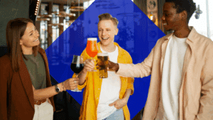 A woman holding a glass of wine cheers with a guy with a glass of cocktail and the other guy with beer