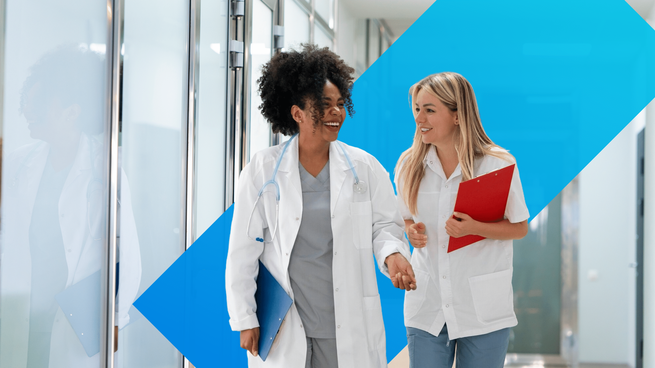Two physicians walking through hospital hallway while discussing patient care